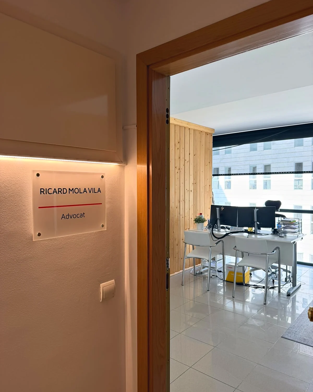Entrada interior del despacho con la placa «Ricard Mola Vila · Advocat» junto a la puerta.